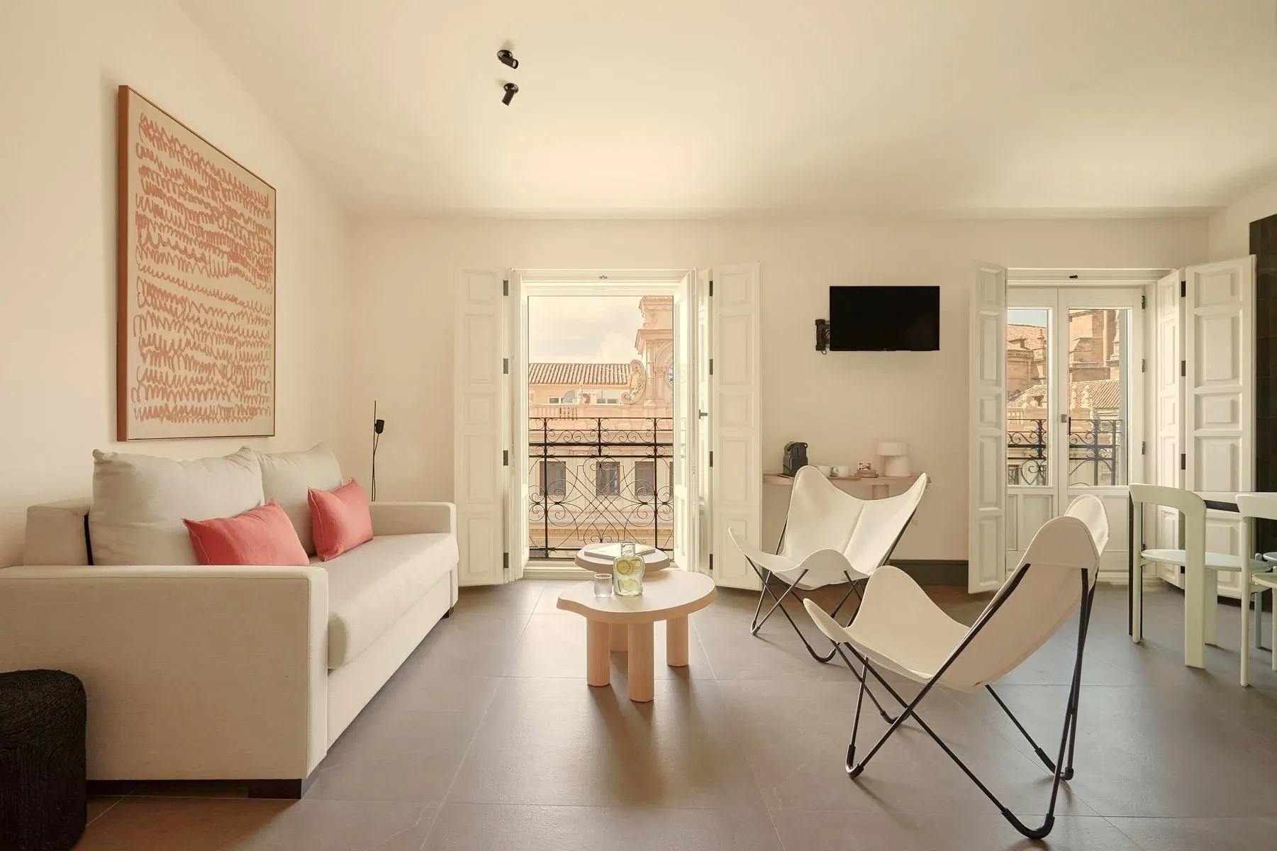 Spacious and bright living room with sofa, butterfly chairs, and city views. U-Sense Granada Gran Vía