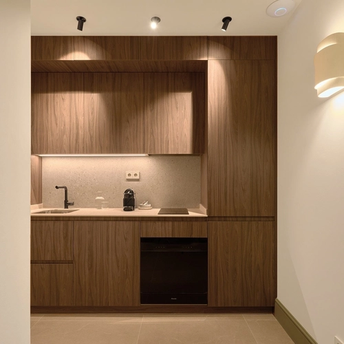 Cocina moderna en hotel, acabados en madera, electrodomésticos integrados y luz ambiental. U-Sense Granada Gran Vía