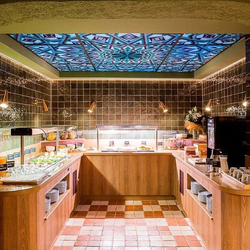 Buffet desayuno hotel con decoración de azulejos y techo geométrico. U-Sense Granada Centro