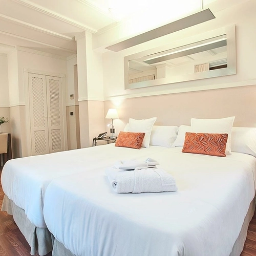 Habitación doble de hotel con camas cómodas, escritorio y espejo. U-Sense Sevilla Centro