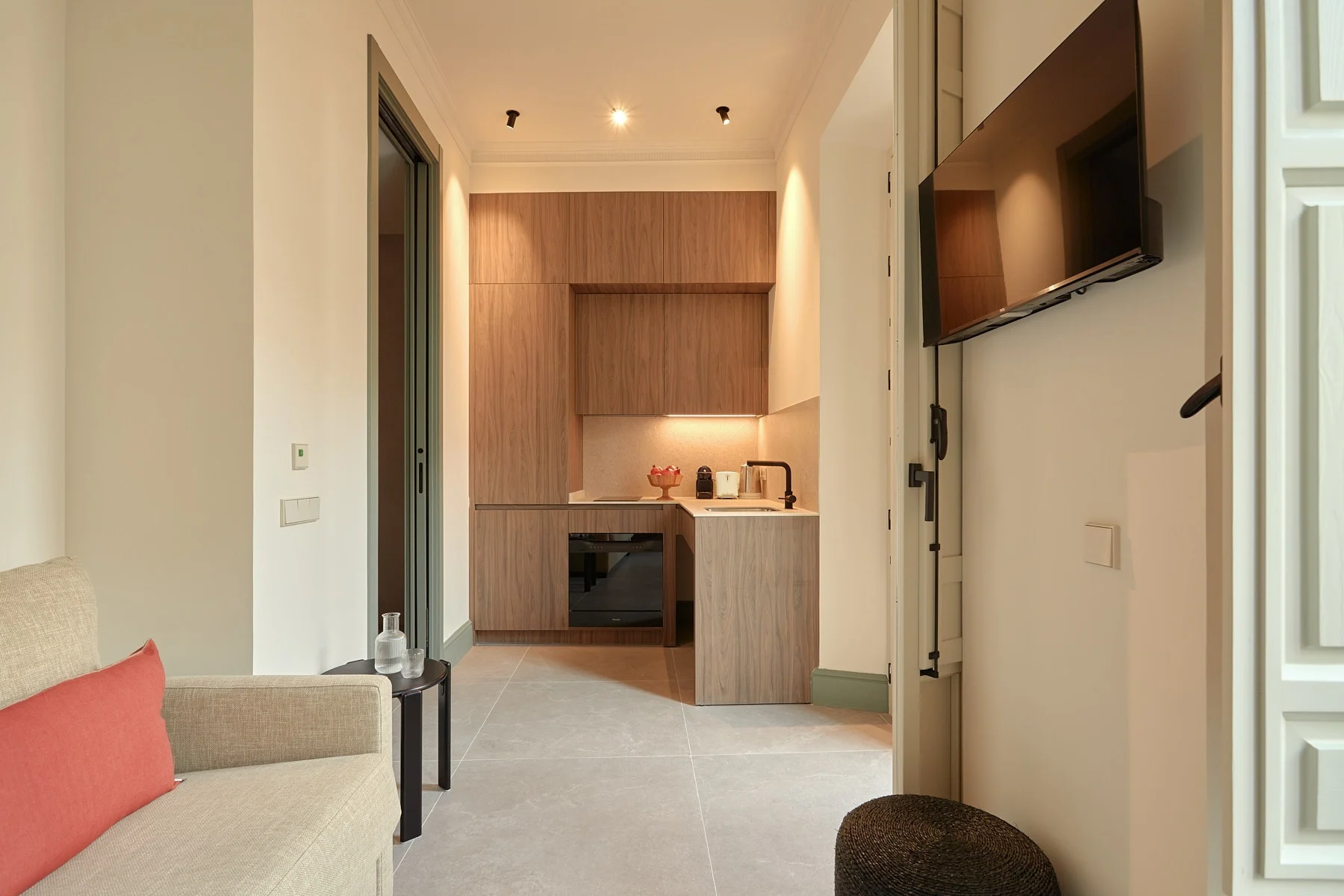 Modern hotel room with kitchenette and seating area, offering U-Sense comforts.
