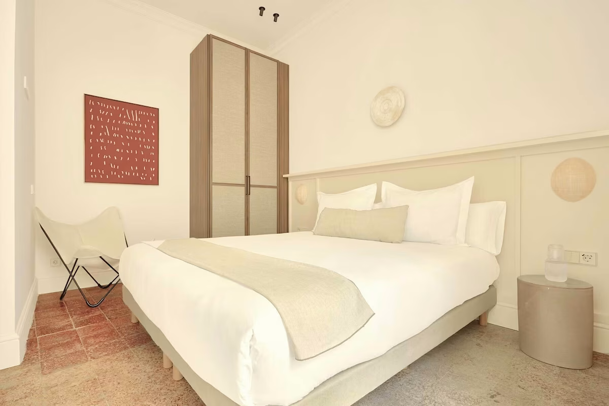 Modern bed with abstract painting and butterfly chair. U-Sense Sevilla Santa Cruz