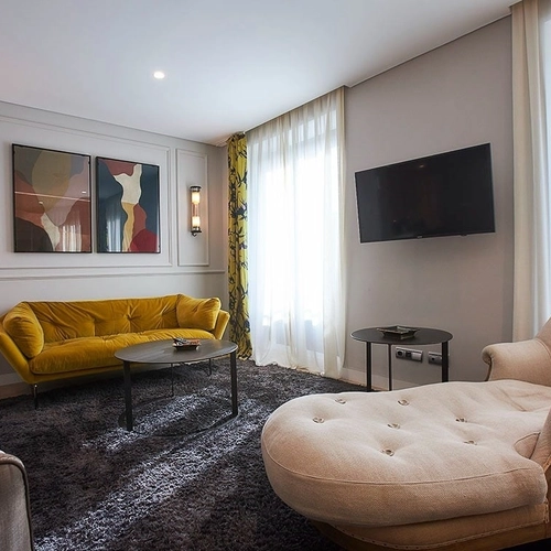 Sofá amarillo y sillón en sala de estar moderna con obras de arte. U-Sense Madrid Santa Ana