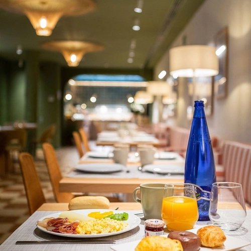 Delicioso desayuno en mesa de hotel con zumo, bollería y tostada. U-Sense Granada Centro
