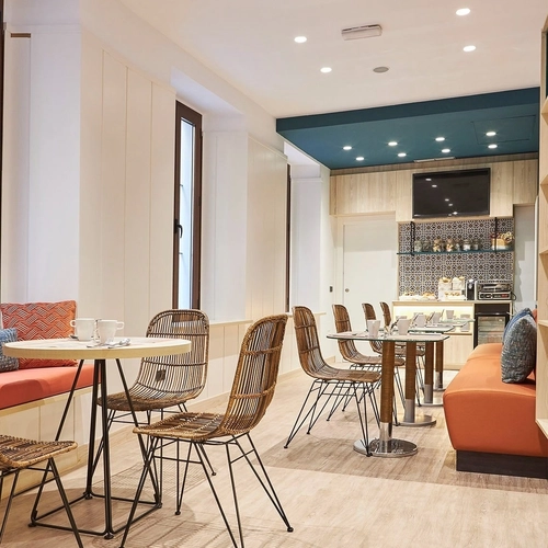 Comedor acogedor con sillas de mimbre y asientos naranja. U-Sense Sevilla Centro