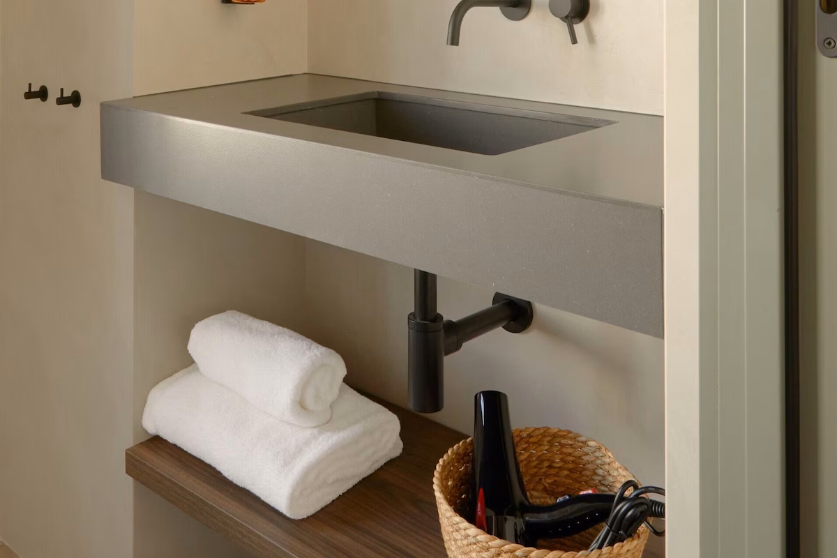 Modern bathroom with sleek concrete sink, towels, and hair dryer U-Sense.