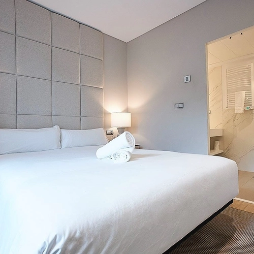 Habitación acogedora con cama matrimonial, cabecero acolchado y baño moderno. U-Sense Madrid Santa Ana