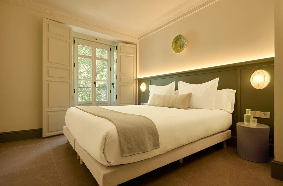 Stylish hotel bedroom with large window, comfortable bed U-Sense, and ambient lighting.