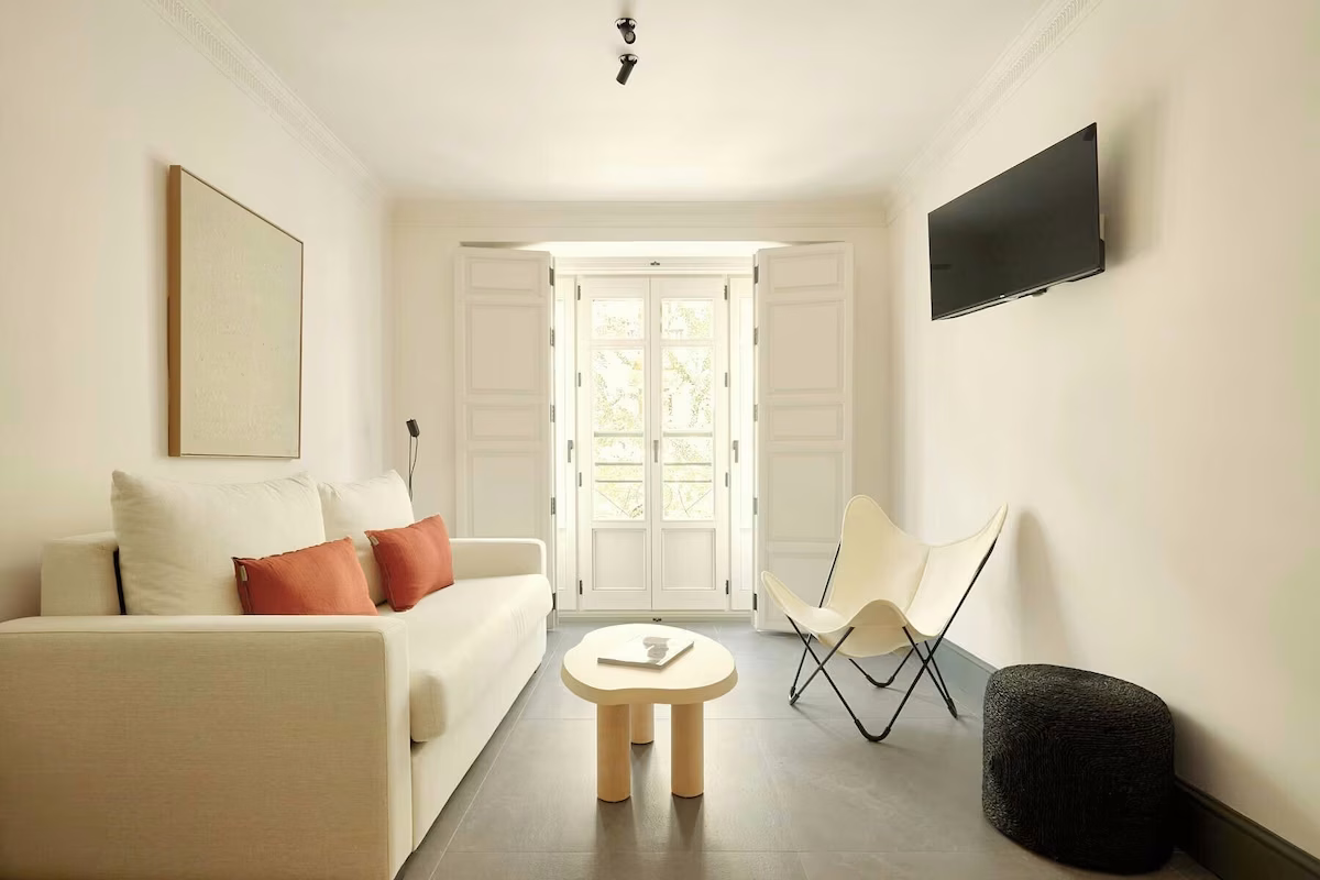 Bright living room with sofa, table, and armchair. U-Sense Sevilla Santa Cruz