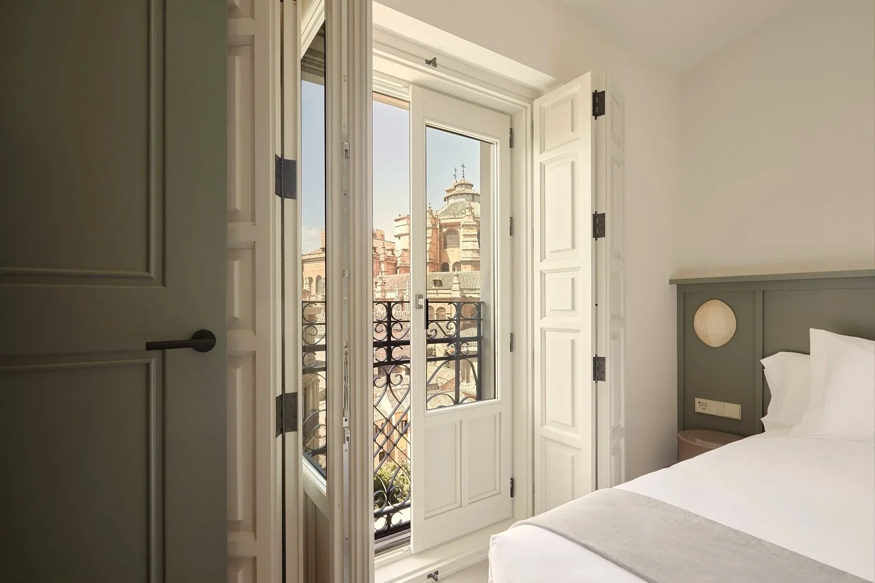 Bright room with French doors opening onto a balcony with city views. U-Sense Granada Gran Vía