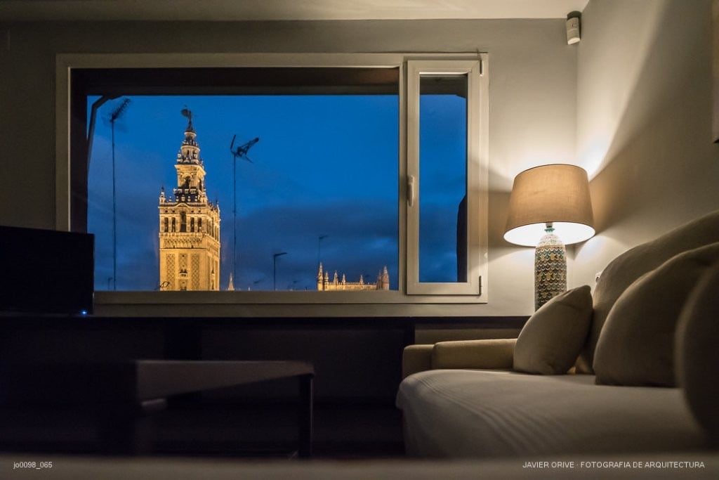 U-Sense Sevilla Santa Cruz | Apartamentos Turísticos en Sevilla: vista de la Giralda iluminada en Sevilla desde habitación de hotel.