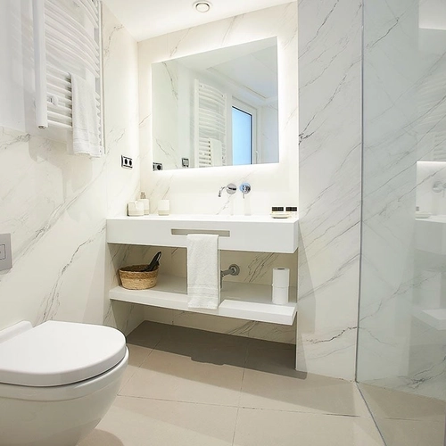 Baño moderno con lavabo, ducha de cristal y pared de mármol. U-Sense Madrid Santa Ana