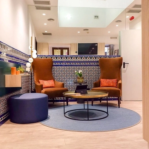 Elegante sala de espera con sillones de cuero y azulejos decorativos. U-Sense Sevilla Centro