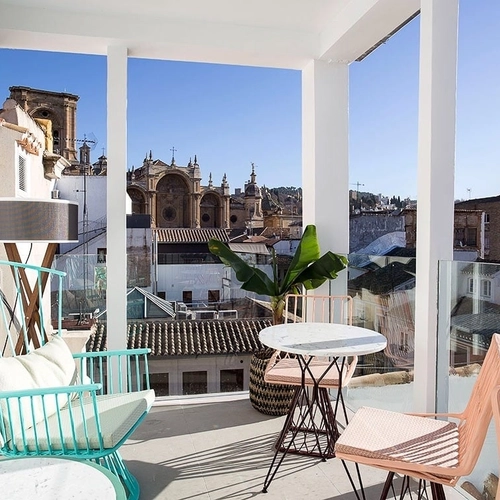 Terraza con sillas coloridas y vistas a la ciudad. U-Sense Granada Catedral