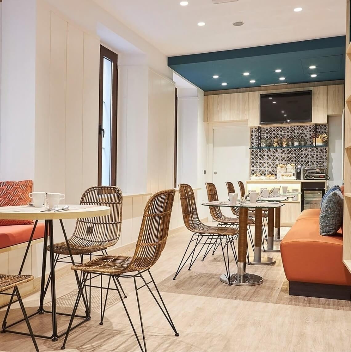 Modern hotel breakfast area with wicker chairs and orange seating. U-Sense