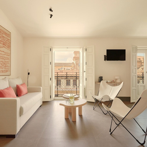 Cómoda sala de estar con sofá, sillas mariposa y balcón con vistas. U-Sense Granada Gran Vía