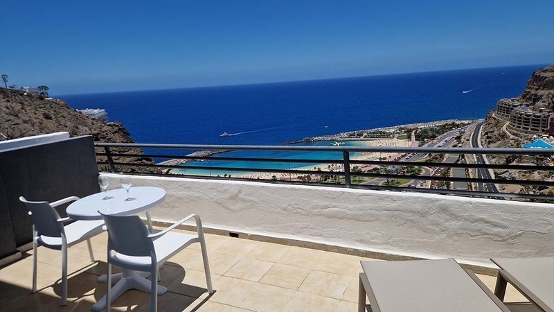 a balcony with a table and chairs overlooking the ocean