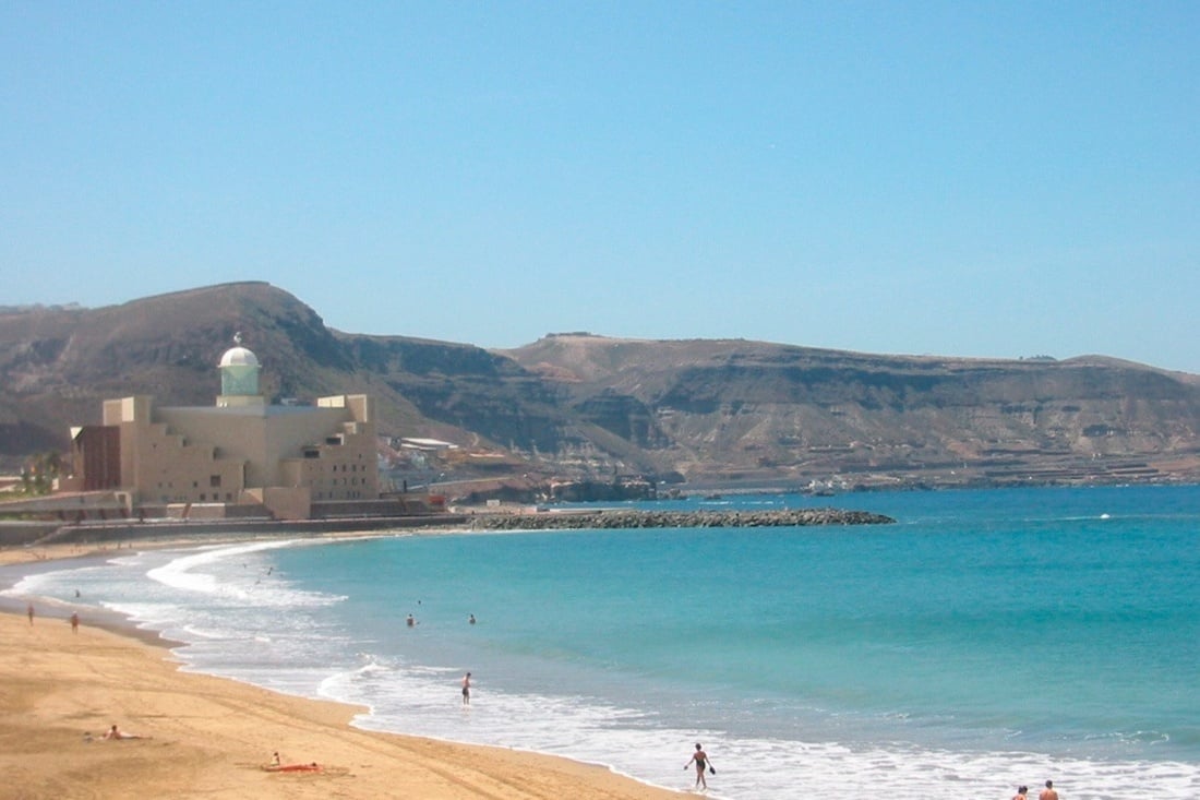 a cliff overlooking the ocean with buildings in the background