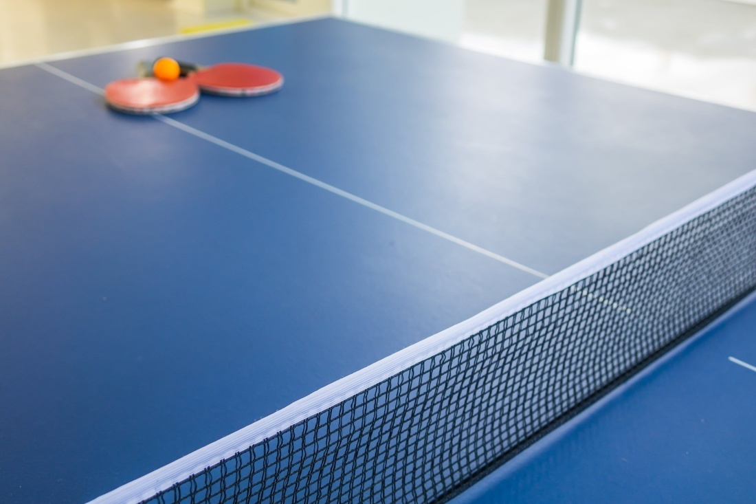 una mesa de ping pong azul con dos raquetas y una pelota