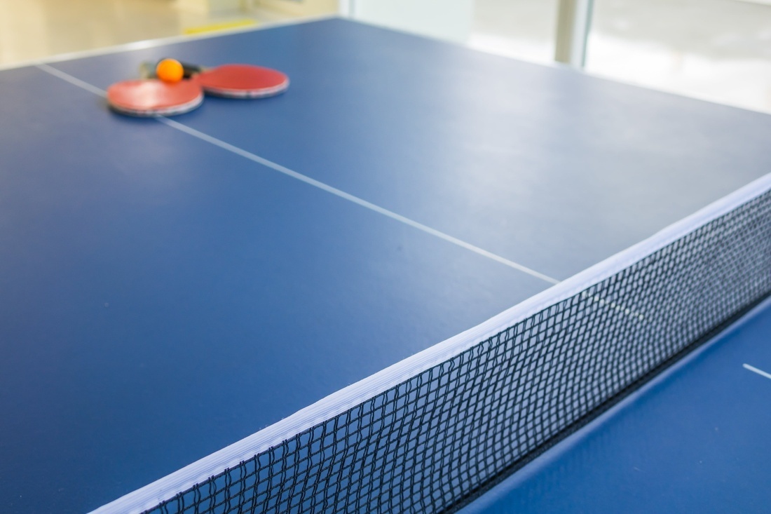 two ping pong rackets and a ball on a blue table