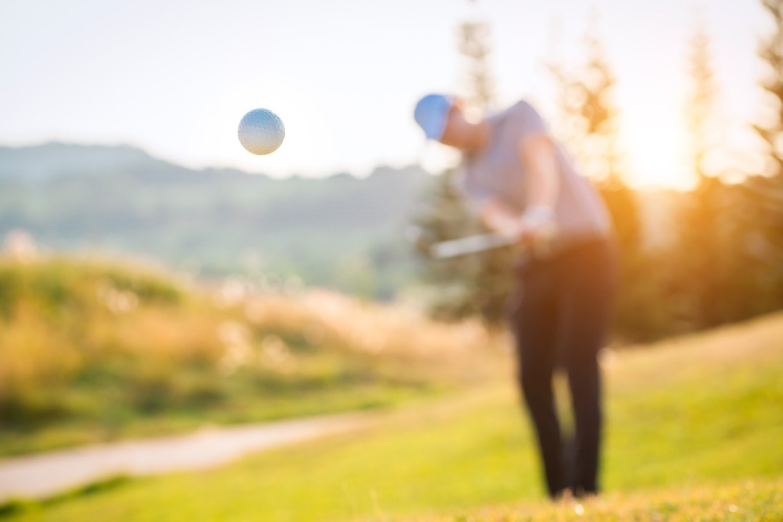 a man is swinging a golf club at a golf ball