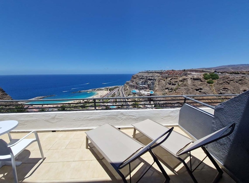 a view of the ocean from a balcony with lounge chairs