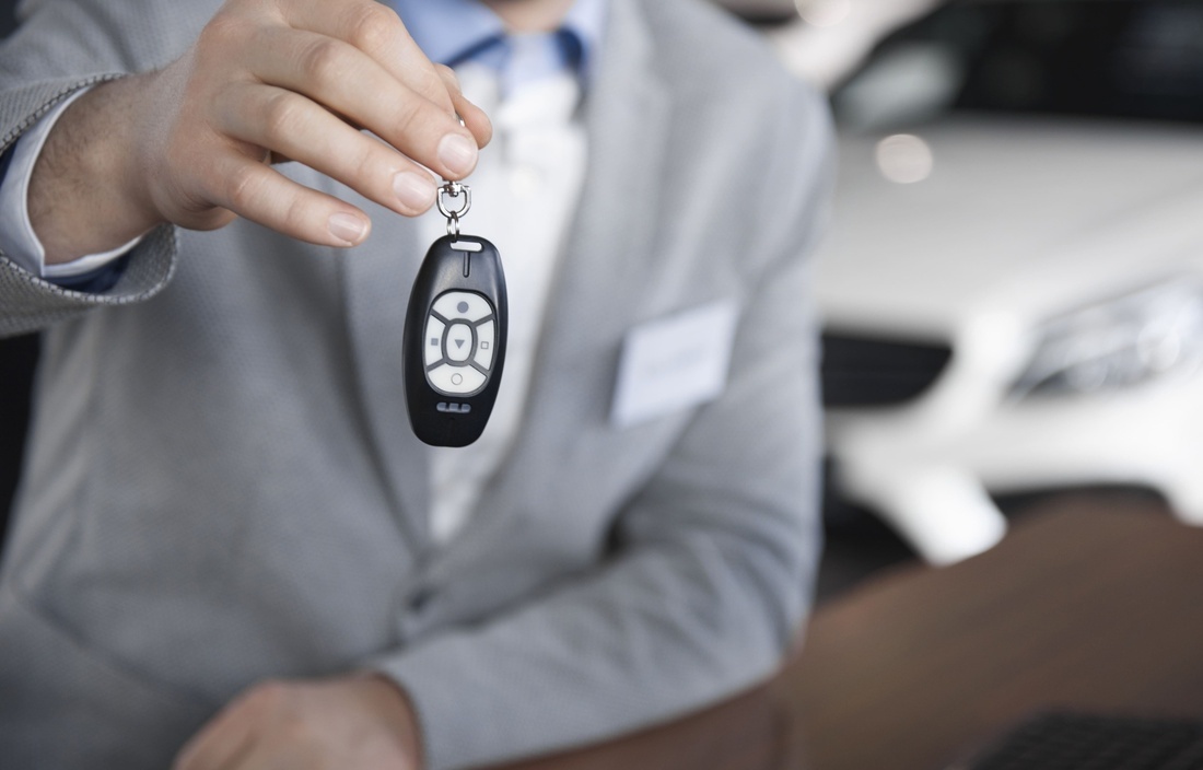 a man in a suit is holding a car key with a remote control on it