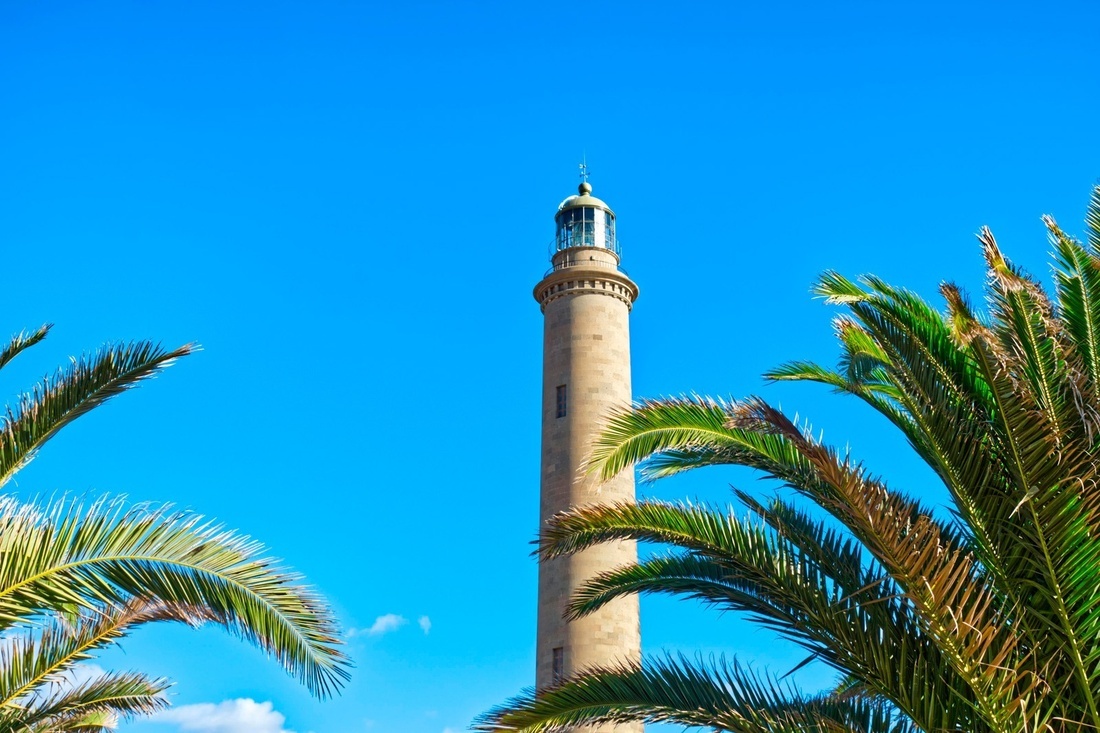 a tall tower with palm trees in front of it