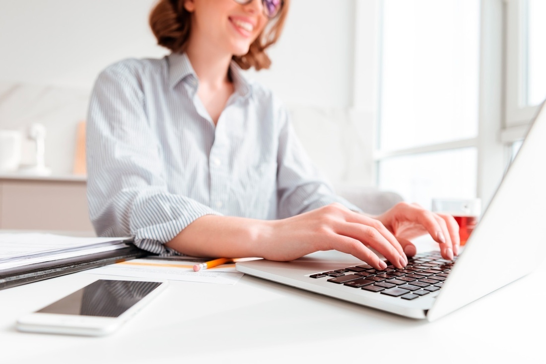 a woman sits at a desk typing on a laptop