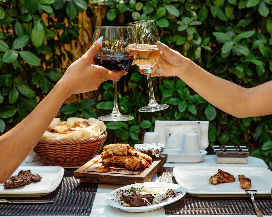 dos mujeres sostienen copas de vino en una mesa con platos de comida