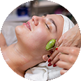 une femme reçoit un massage du visage avec un rouleau de jade .