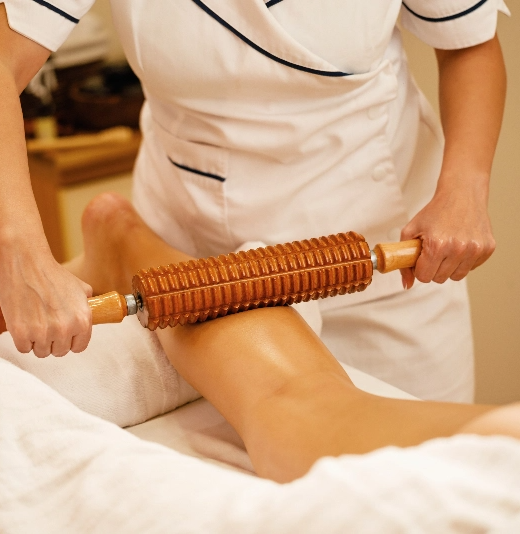 une femme reçoit un massage avec un rouleau en bois