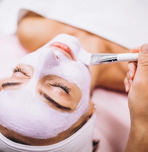 une femme reçoit un masque violet sur son visage avec un pinceau