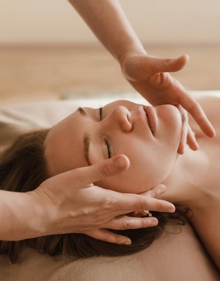 une femme reçoit un massage du visage avec ses yeux fermés