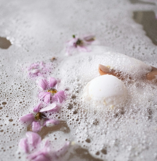 une boule de savon se trouve dans une baignoire avec des fleurs violettes