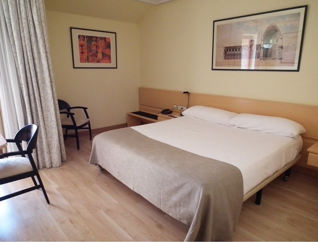 a hotel room with a large bed and two framed pictures on the wall