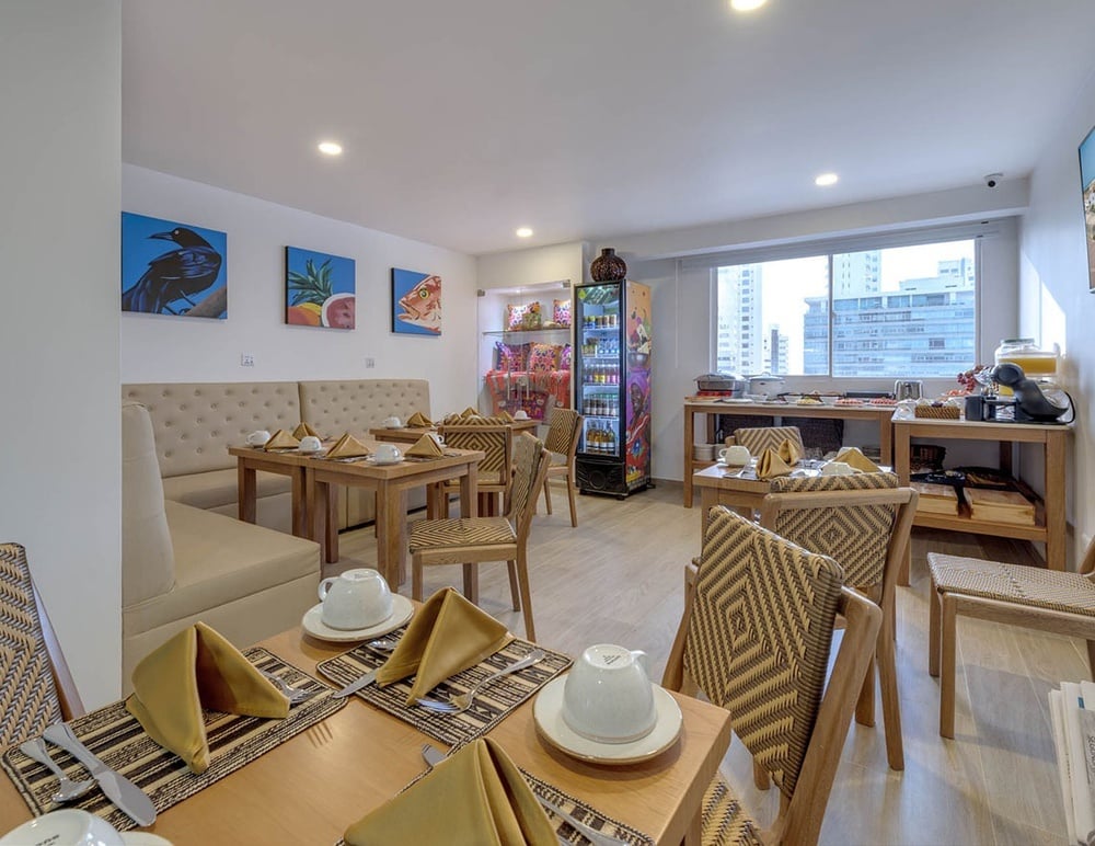 uma sala de jantar com mesas e cadeiras e uma geladeira