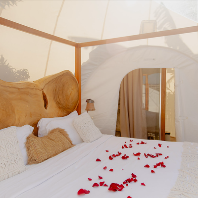 a bed with white sheets and red petals on it