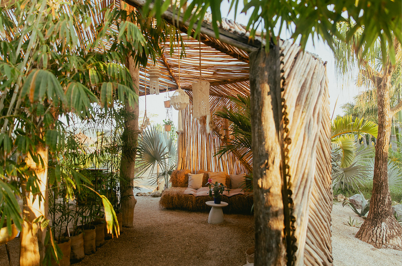 a covered area with a couch and a table under a thatched roof