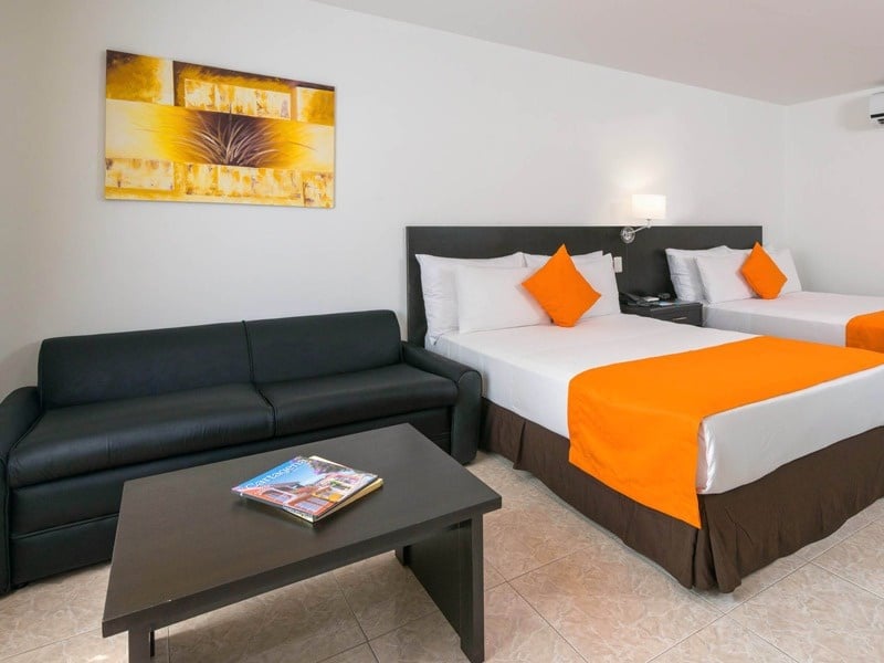 um quarto de hotel com duas camas e um sofá