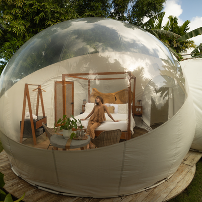 a woman is sitting on a bed in a bubble tent