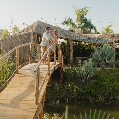 a man and woman standing on a wooden bridge over a body of water