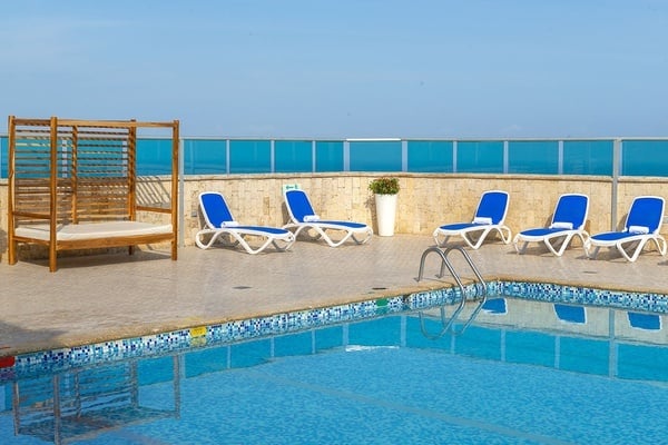 una piscina con sillas azules y una cama de madera