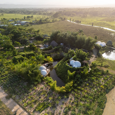 an aerial view of a lush green field with a small pond