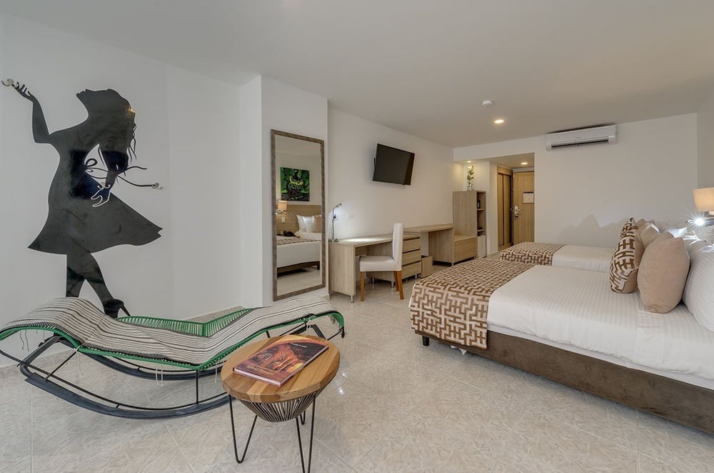 um quarto de hotel com duas camas e uma cadeira de balanço