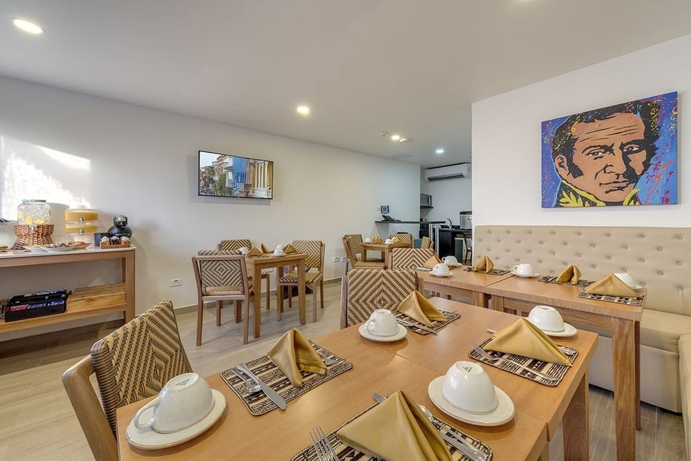 uma sala de jantar com mesas e cadeiras e uma pintura de um homem na parede