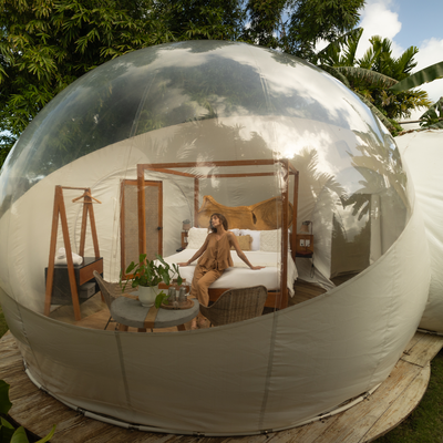 a woman sits on a bed in a bubble tent