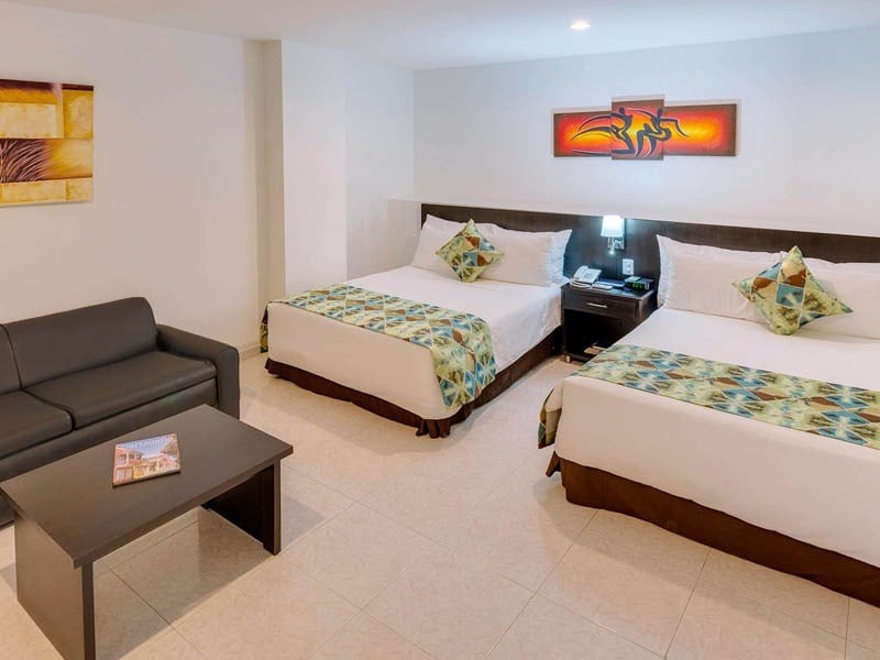 um quarto de hotel com duas camas e um sofá