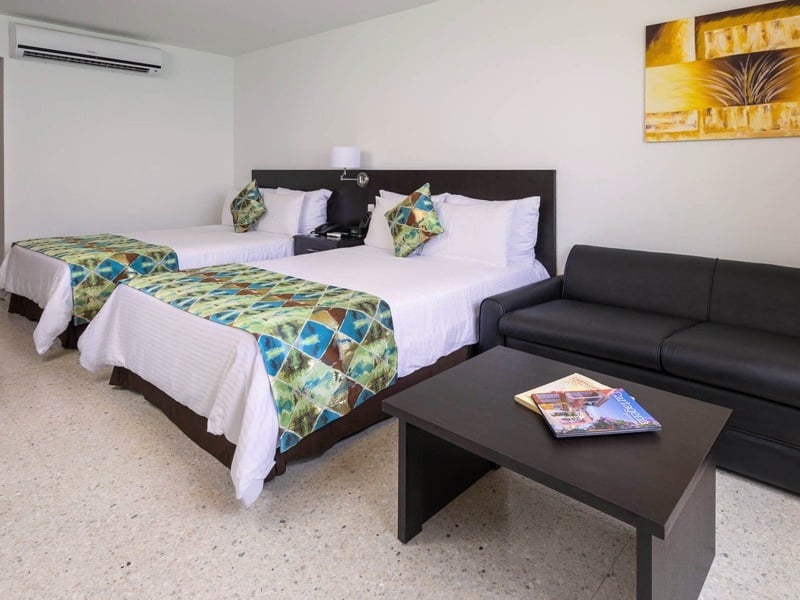 um quarto de hotel com duas camas e um sofá