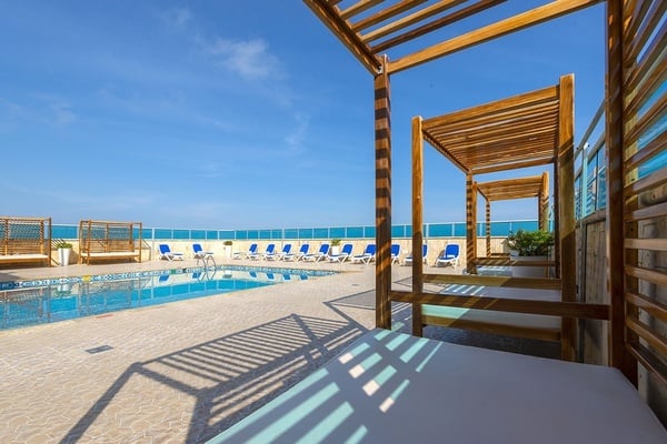 una piscina rodeada de sillas y dosel de madera